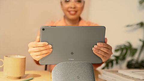 Eine Nutzerin nimmt das Google Pixel Tablet von seinem Ladedock.