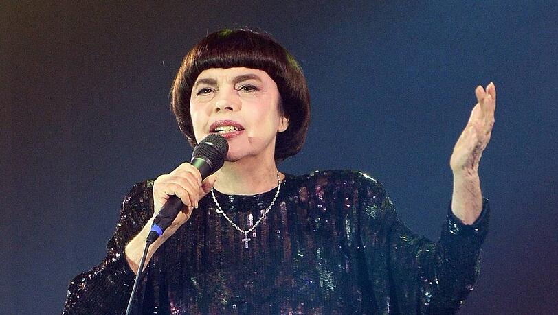 Schwarzes Kleid, Pagenfrisur, erhobene Hand: Mireille Mathieu steht noch auf der Bühne wie vor 50 Jahren.